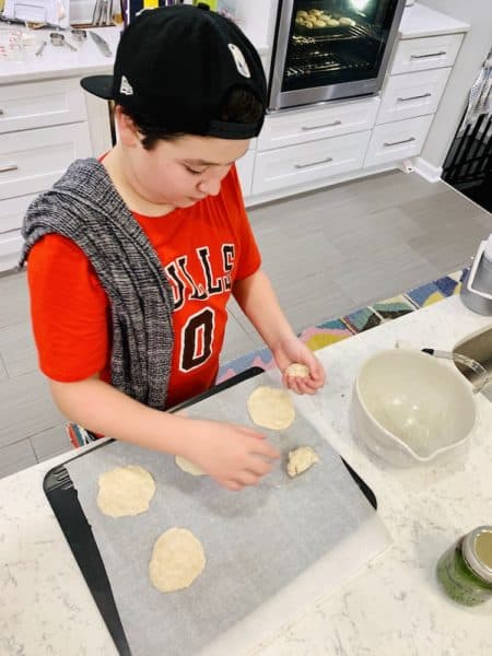 teenage boy baking communion bread in kitchen 