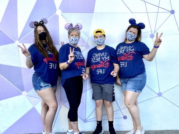 Disney family in masks in front of Magic Kingdom Purple Wall 2020