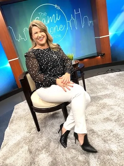 Sami Cone sitting on The Sami Cone Show set in Lilly Pulitzer Idina silk top and winter white jeans