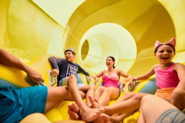 Family of parents and children on a large group raft on a waterslide at Great Wolf Lodge waterpark.